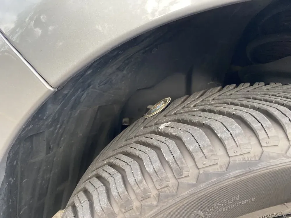 Close-up of a worn tire's tread inside a vehicle's wheel well